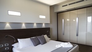 A modern hotel room with a large bed, a bedside table with a phone and notepad, and a wardrobe with sliding doors. - HOTEL SELENE POMEZIA (Pomezia)