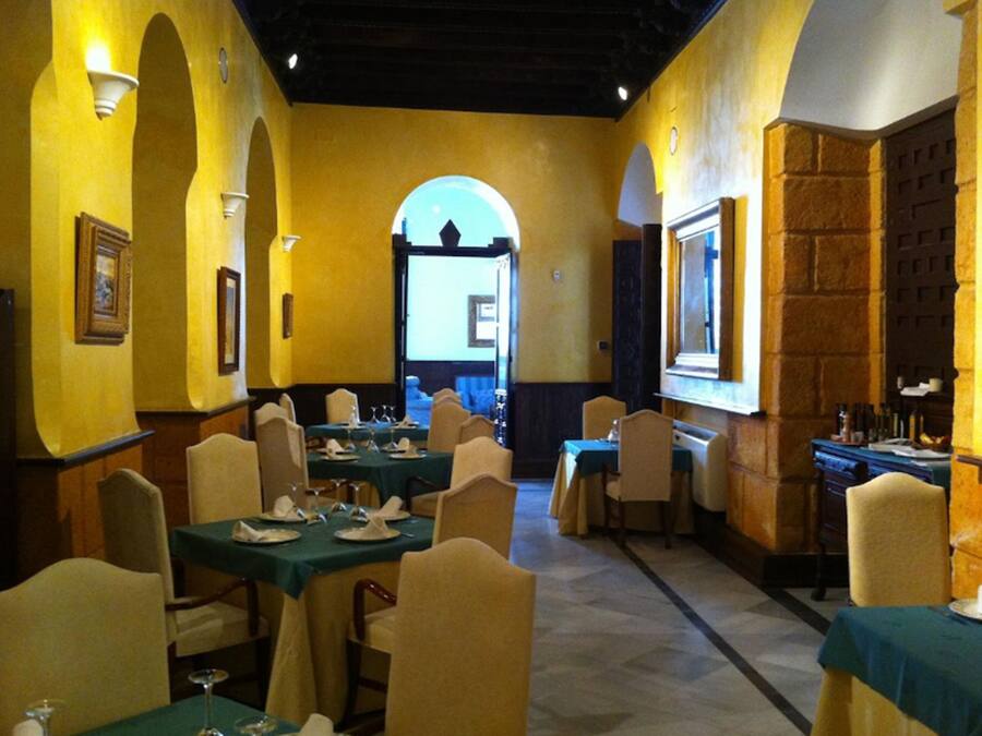 Un restaurante con mesas dispuestas para comer, paredes amarillas y arcos.