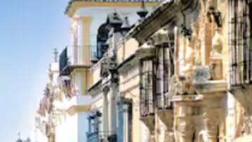 Calle flanqueada por edificios históricos con fachadas y balcones ornamentados.