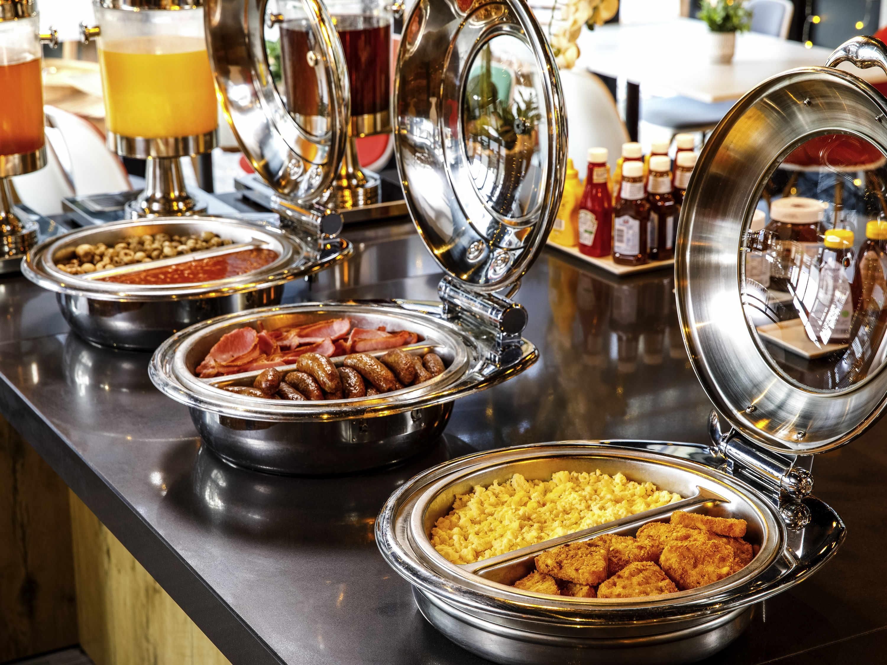 A buffet with various food items including sausages, ham, and fried chicken.