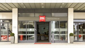 L'entrée de l'hôtel Bristol Centre Harbourside, avec un comptoir d'accueil, des portes vitrées et une enseigne rouge « ibis ».
