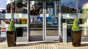 The exterior of the ibis hotel with a glass entrance, automatic doors, and two potted plants. - ibis Bristol Centre (Bristol)
