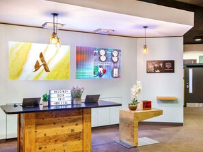 A reception desk with a sign reading 'WELCOME DESK IBIS,' a laptop, and a potted plant. - ibis Bristol Centre (Bristol)