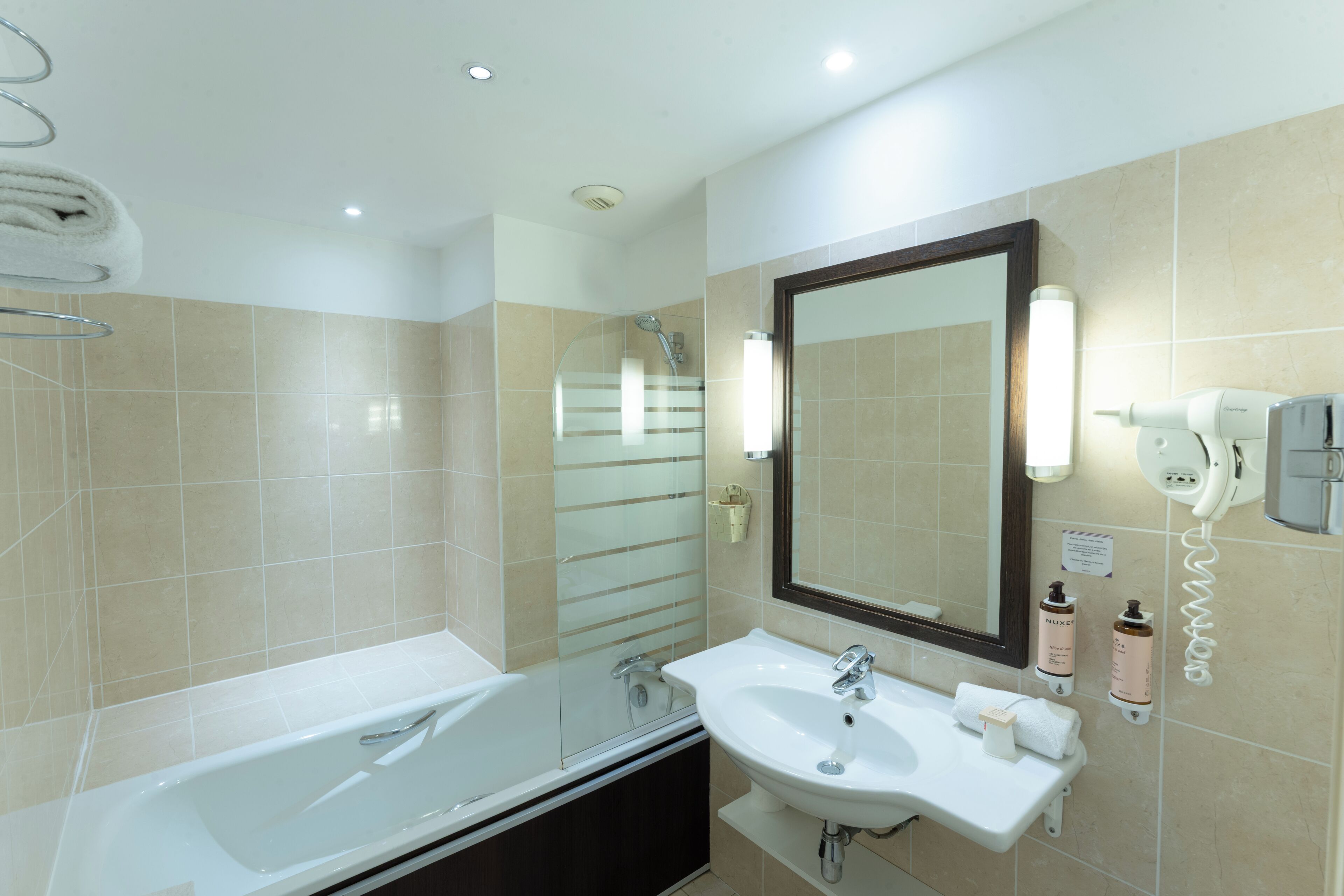 Une salle de bain moderne avec une baignoire, un lavabo et un grand miroir.