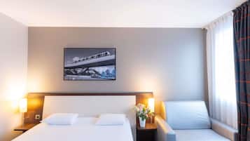A hotel room with a bed, two bedside tables with lamps, a chair, and a wall-mounted picture.