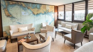 Una sala de estar moderna con un gran mapa mundial en la pared, asientos cómodos y ventanas amplias.
