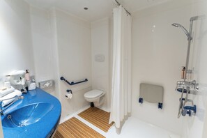 A bathroom with a blue sink, toilet, and shower area.