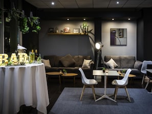Una sala moderna con un sofá, dos sillas blancas, una mesita y una mesa decorativa con letras iluminadas.