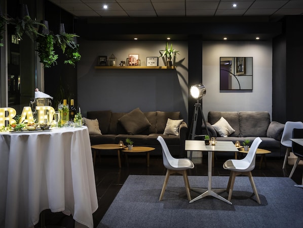 Un salon moderne comprenant un canapé, deux fauteuils blancs, une petite table et une table décorative agrémentée de lettres illuminées.