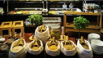Un bufé con diversas opciones de comida, entre ellas frutas, cereales y salsas.