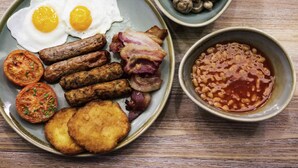 A plate with eggs, sausages, bacon, tomatoes, and beans.