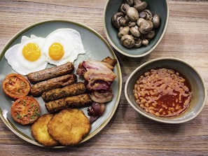 A plate with eggs, sausages, bacon, tomatoes, and beans.