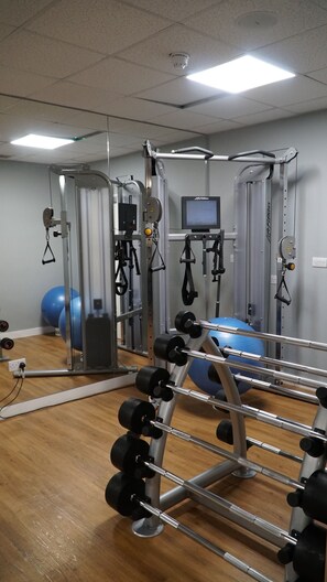 A gym with various exercise equipment, including a cable machine, weight stacks, and exercise balls. - Novotel Reading Centre (Reading)