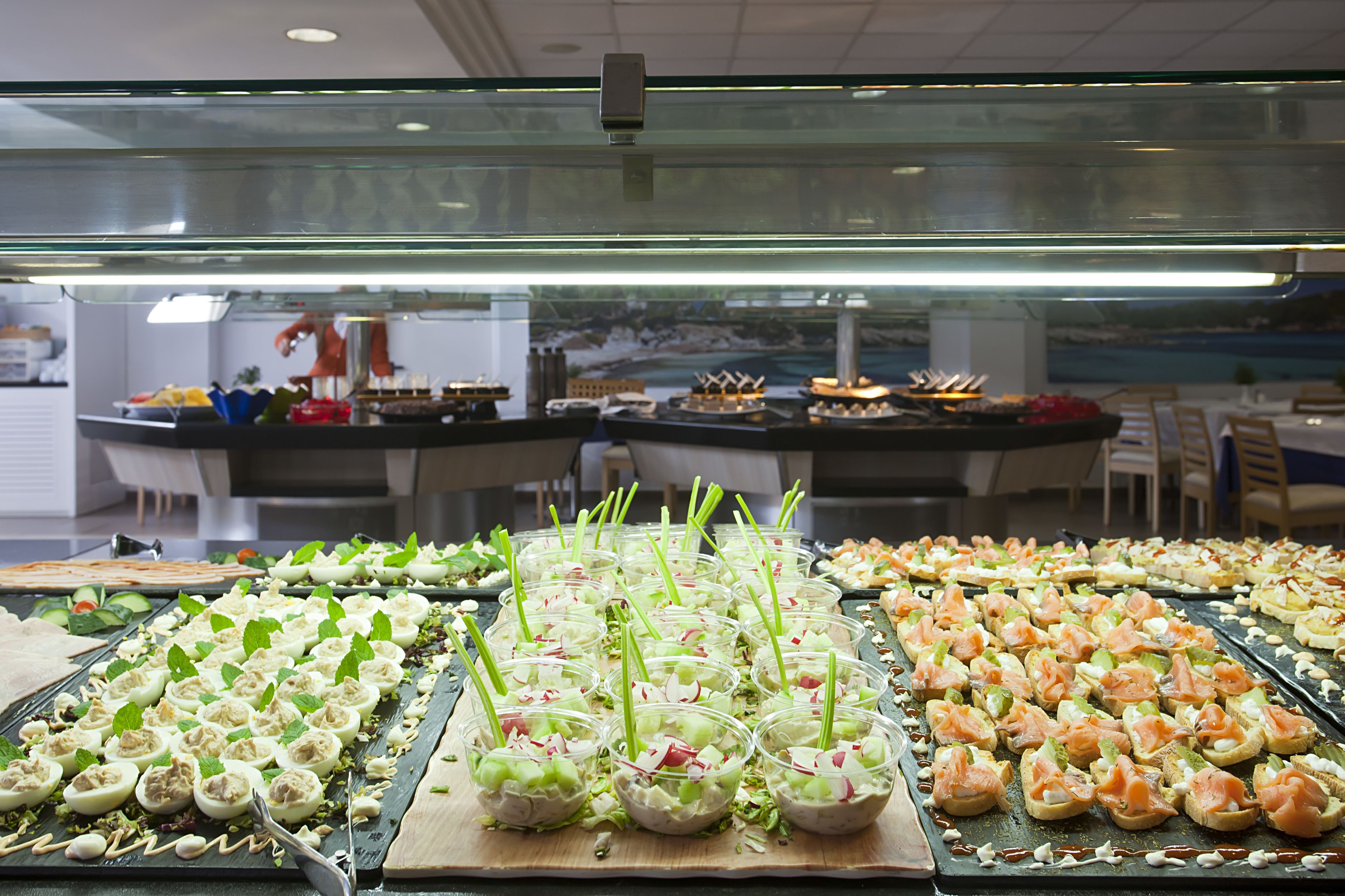 Un bufé con diversas opciones de comida, como ensaladas, sándwiches y aperitivos.