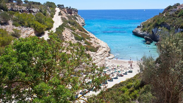 Eine Küstenlandschaft mit Strand, felsigen Klippen und blauem Meer.
