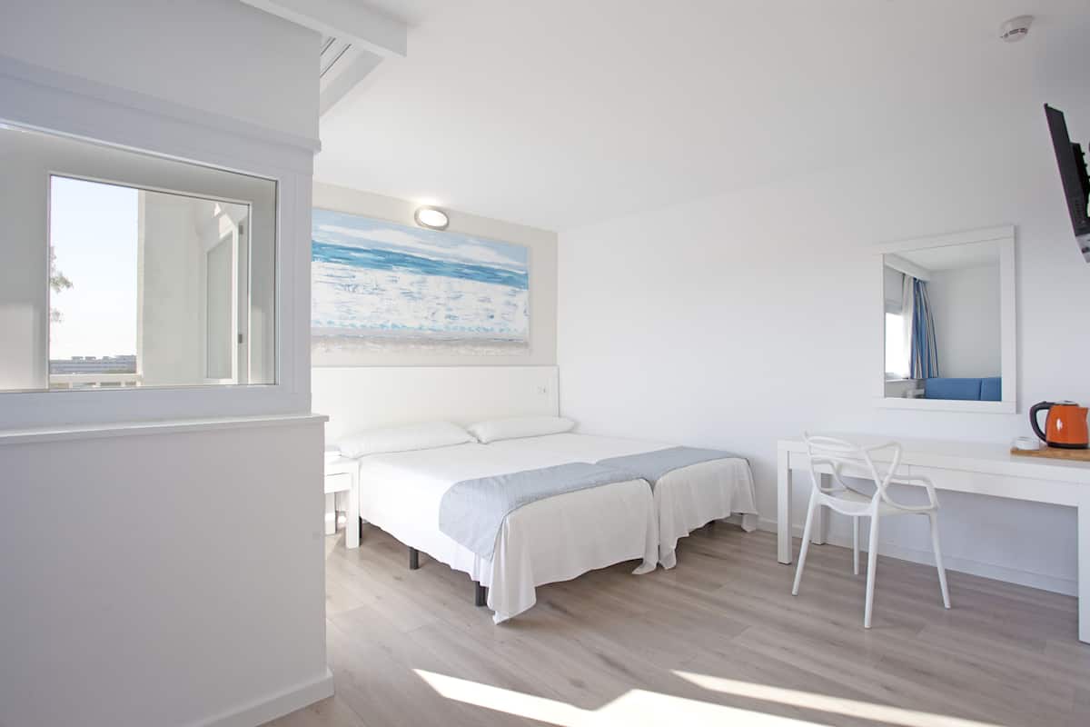 Un dormitorio con cama, escritorio, silla y un cuadro en la pared.