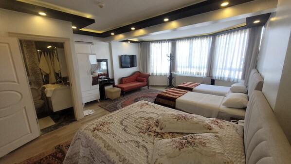 A hotel room with a large bed, a sofa, a desk, and a TV.