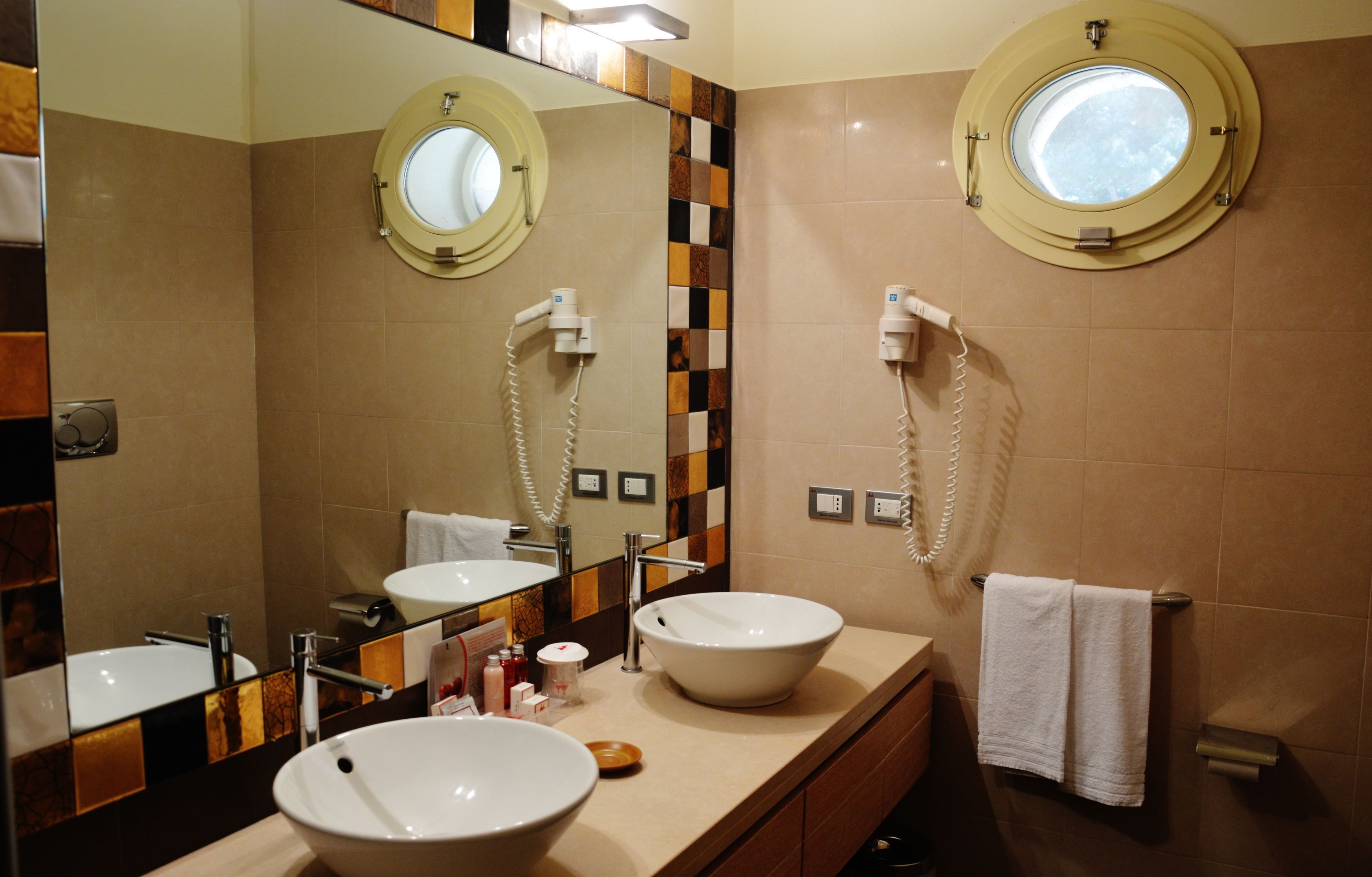 Un baño con dos lavamanos, un espejo y un perchero para toallas.