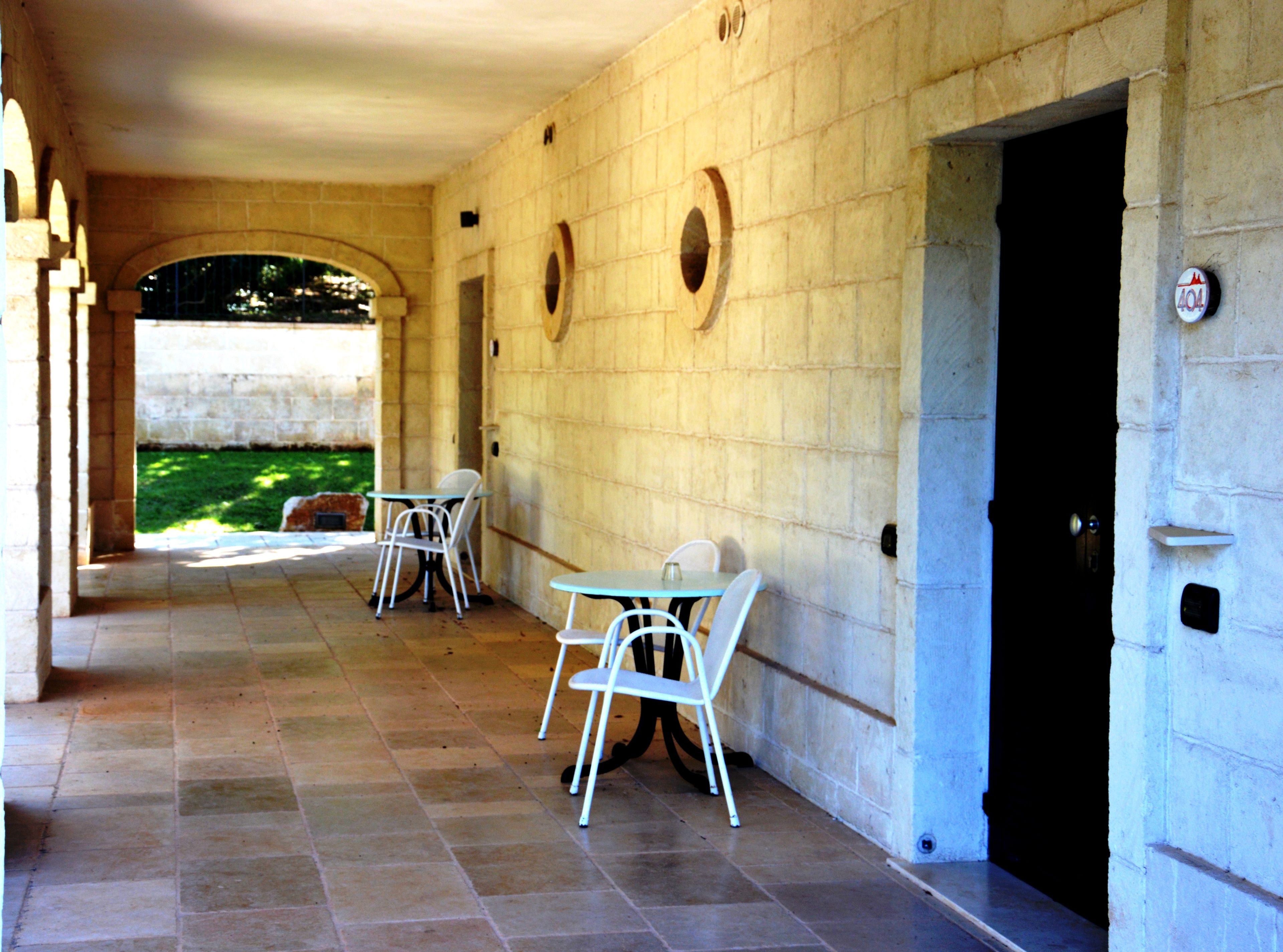 Un espace extérieur abrité, doté de murs en pierre, de deux tables avec des chaises et d’une porte.