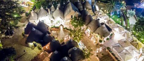 A resort with thatched-roof structures, outdoor seating, and a landscaped garden.