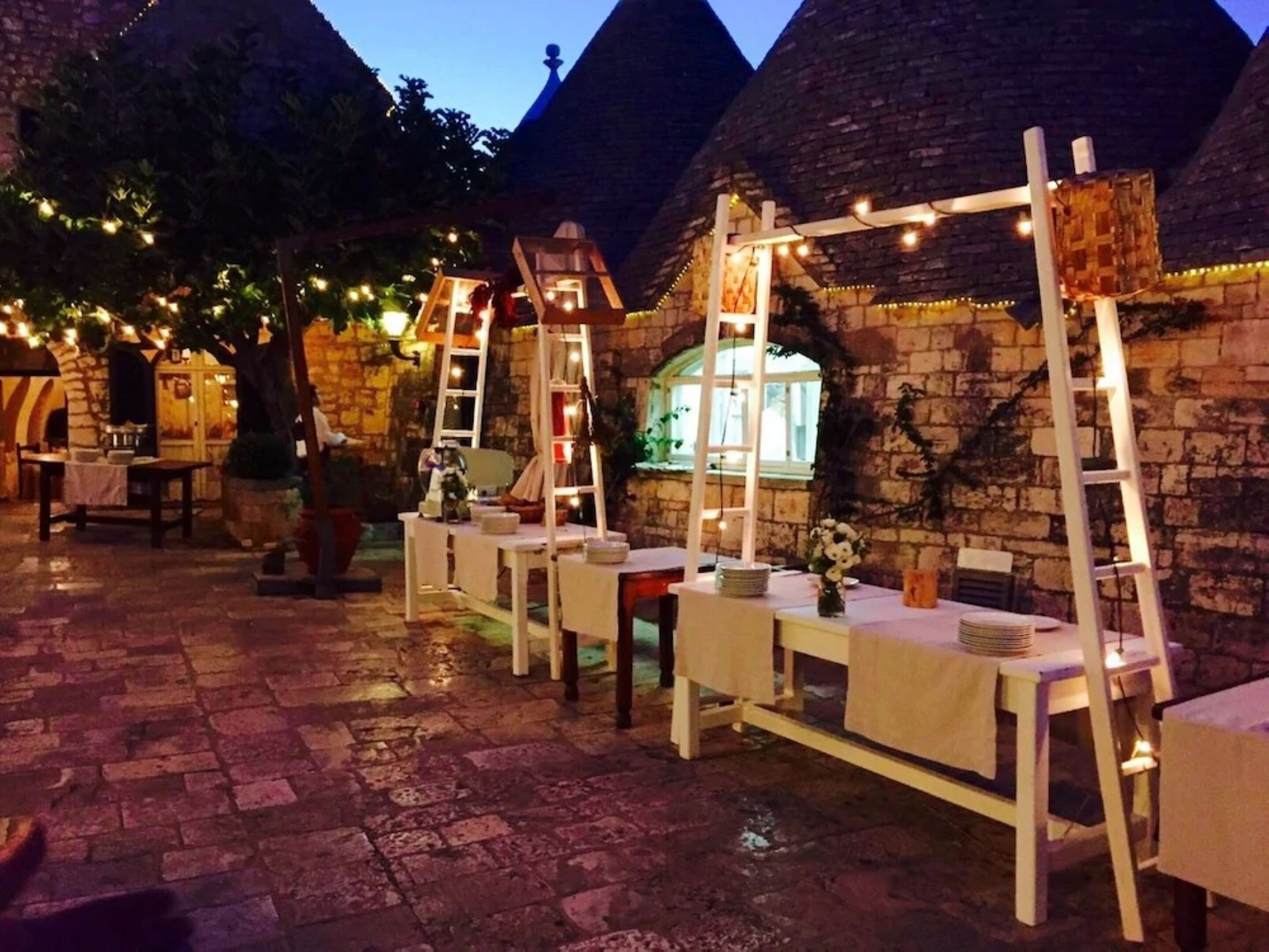 Un área de comedor al aire libre con muros de piedra y mesas dispuestas para comer.
