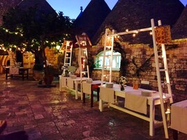 Zona pranzo all'aperto con pareti in pietra e tavoli apparecchiati.