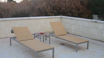 Dos sillones de relax con estructura metálica y asientos tejidos en un patio con baldosas.