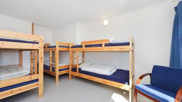 A dormitory room with bunk beds, a wooden chair, and a ceiling light.