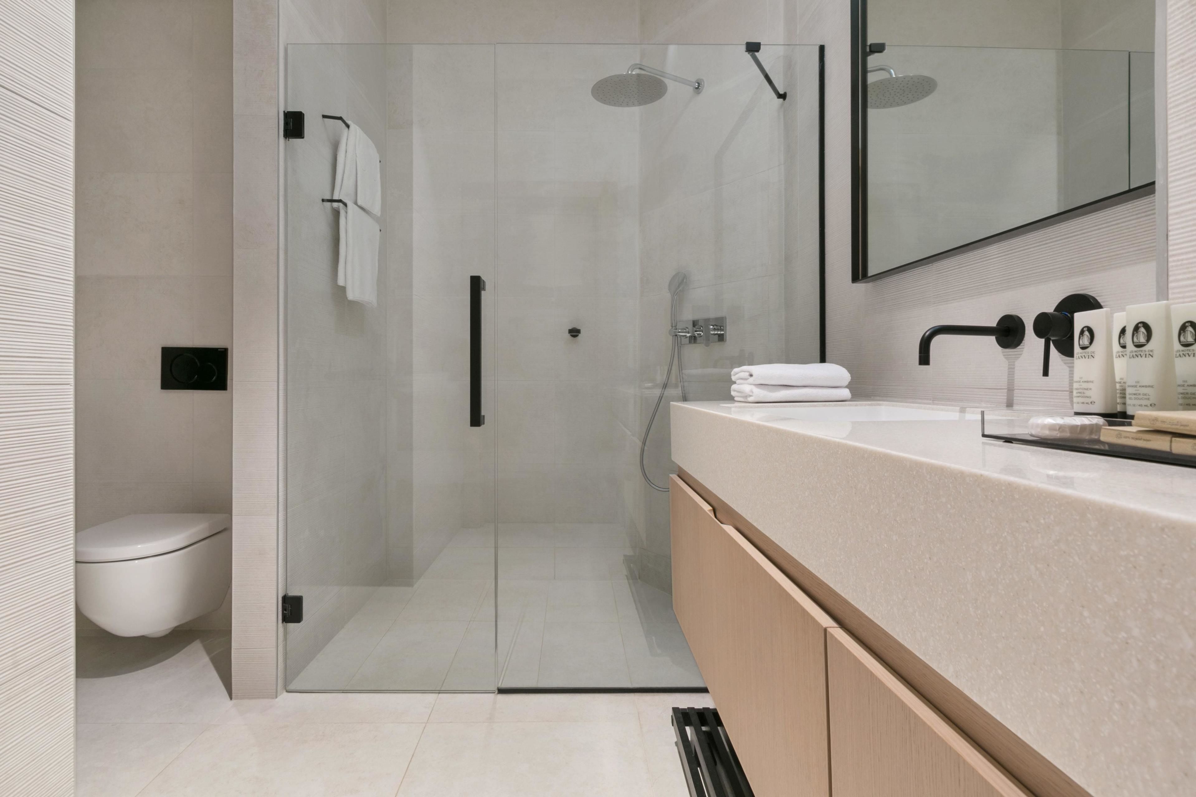 Un baño moderno con cabina de ducha de vidrio, tocador con encimera y un inodoro.