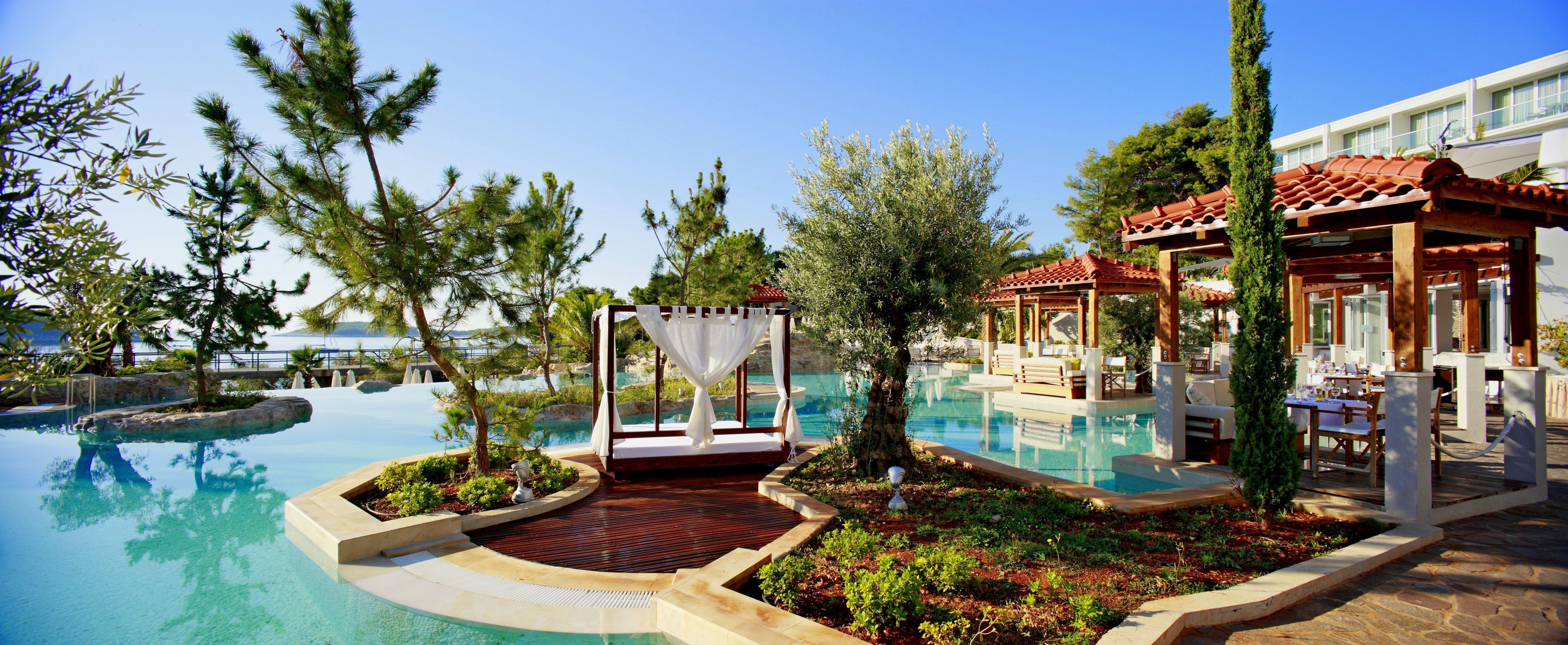 A resort pool area with a gazebo, lounge chairs, and a dining area.