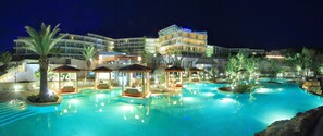 A hotel with a large swimming pool, multiple lounge areas, and a well-lit building facade. - Amfora Hvar Grand Beach Resort (Hvar)