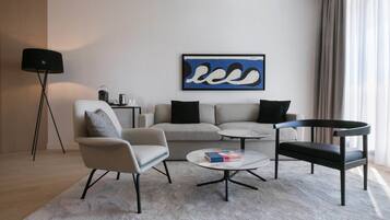 Un salon moderne comprenant un canapé, un fauteuil, une table basse et une table d’appoint avec une lampe.
