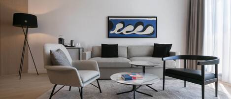 Ein modernes Wohnzimmer mit Sofa, Sessel, Couchtisch und Beistelltisch mit Lampe.