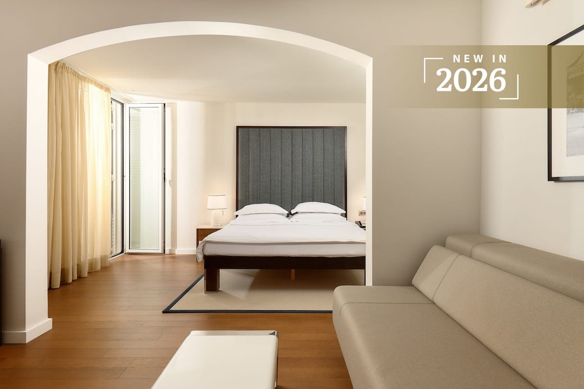 Ein modernes Hotelzimmer mit einem Bett, einer Couch und einem großen Fenster.