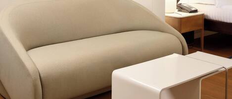 A beige sofa and a white table in a hotel room.