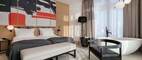 A modern bedroom with a large bed, bedside tables, a bench, a bathtub, and a large abstract painting on the wall.