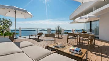 Relax in style with comfortable lounge chairs and dining areas under spacious umbrellas, offering breathtaking sea views.