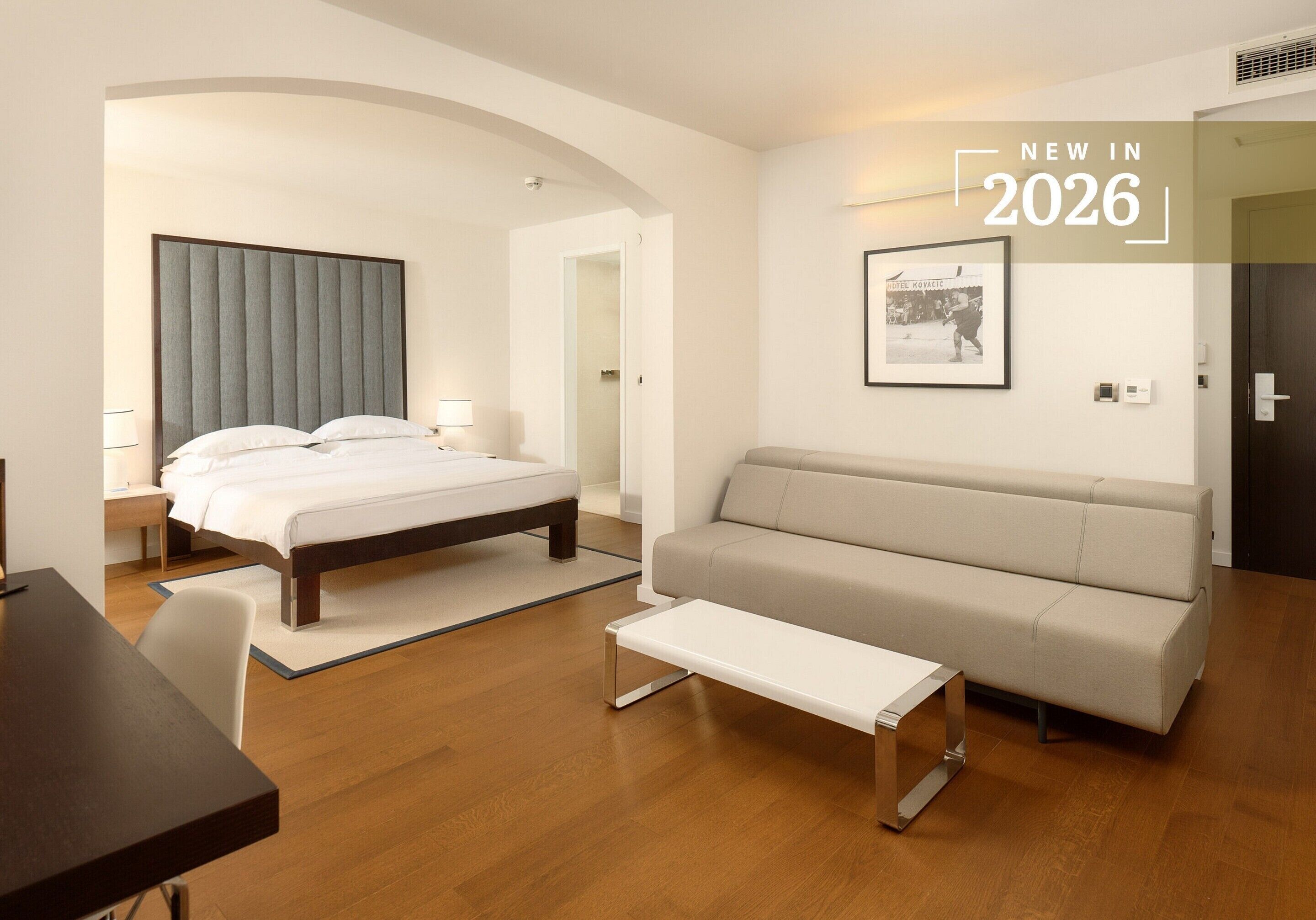 Een moderne hotelkamer met een bed, een bank, een bureau en een klein tafeltje.