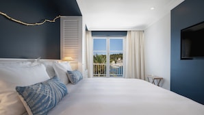 Une chambre d’hôtel avec un grand lit, une télévision, un balcon donnant sur la ville et une fenêtre avec des rideaux.
