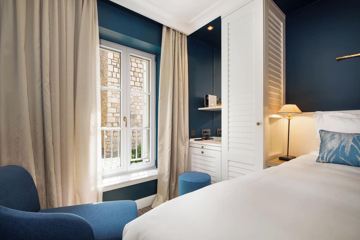 Un dormitorio con una cama, un escritorio, una silla y una ventana con cortinas.