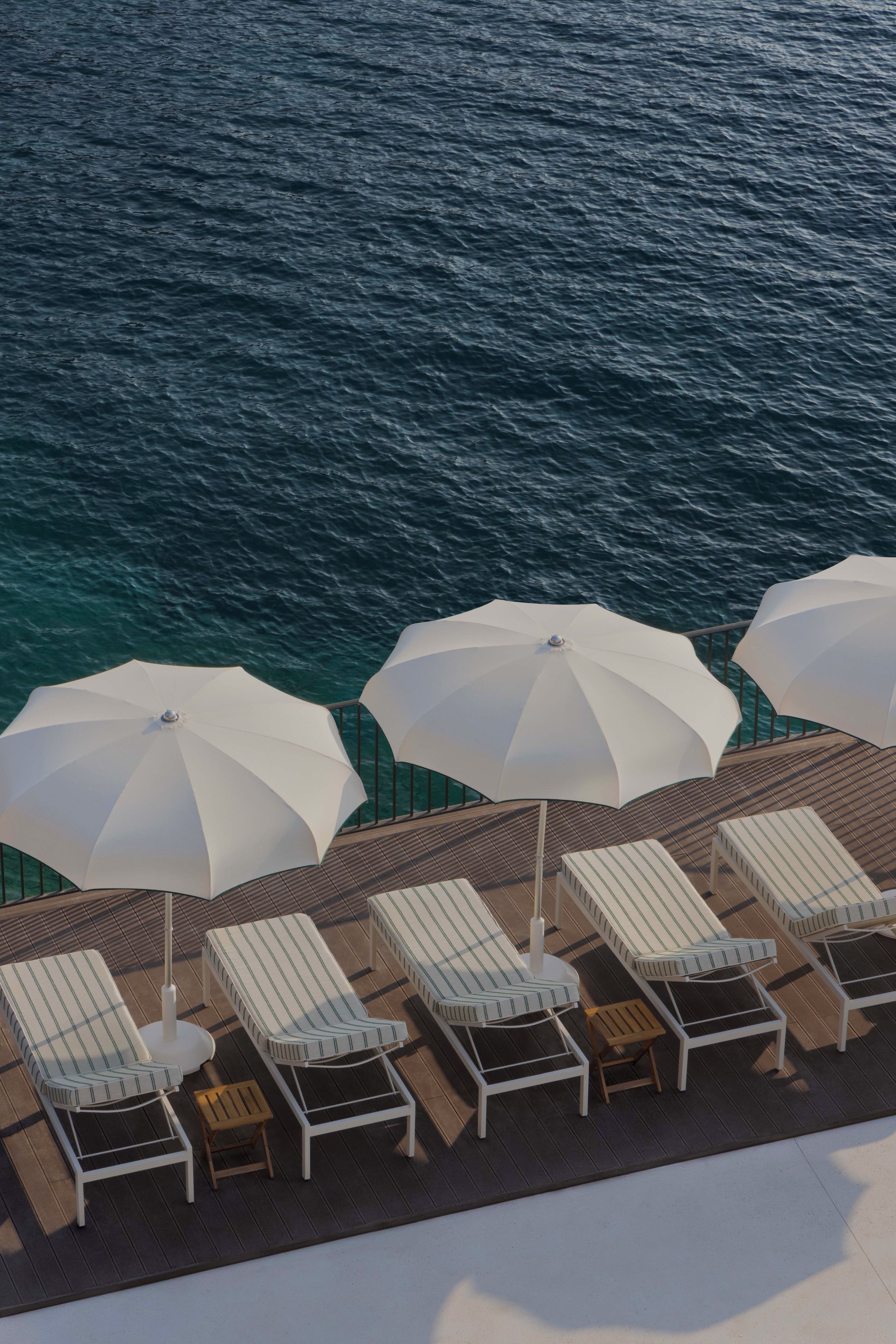 A deck with sun loungers and umbrellas overlooking the sea.
