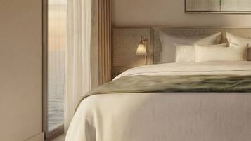 A modern hotel room with a large bed, a view of the city, and a large window with sheer curtains.