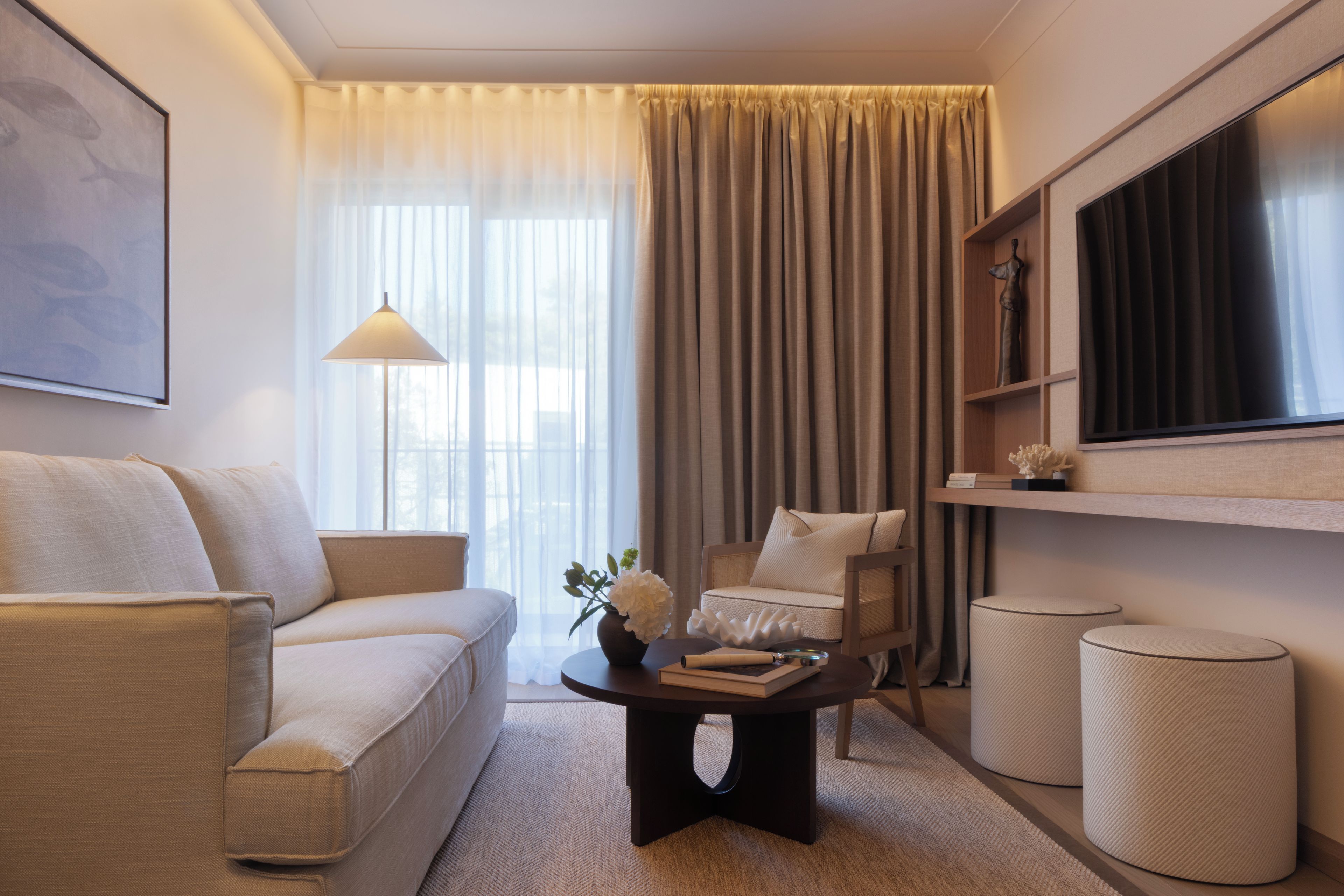 A modern living room with a sofa, armchair, coffee table, and a television on a stand.
