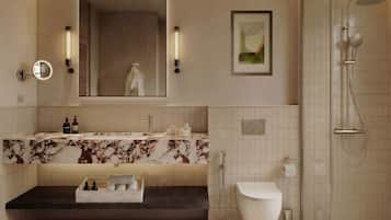 A modern bathroom with a marble vanity, a large mirror, a framed artwork, a shower enclosure, and a toilet.