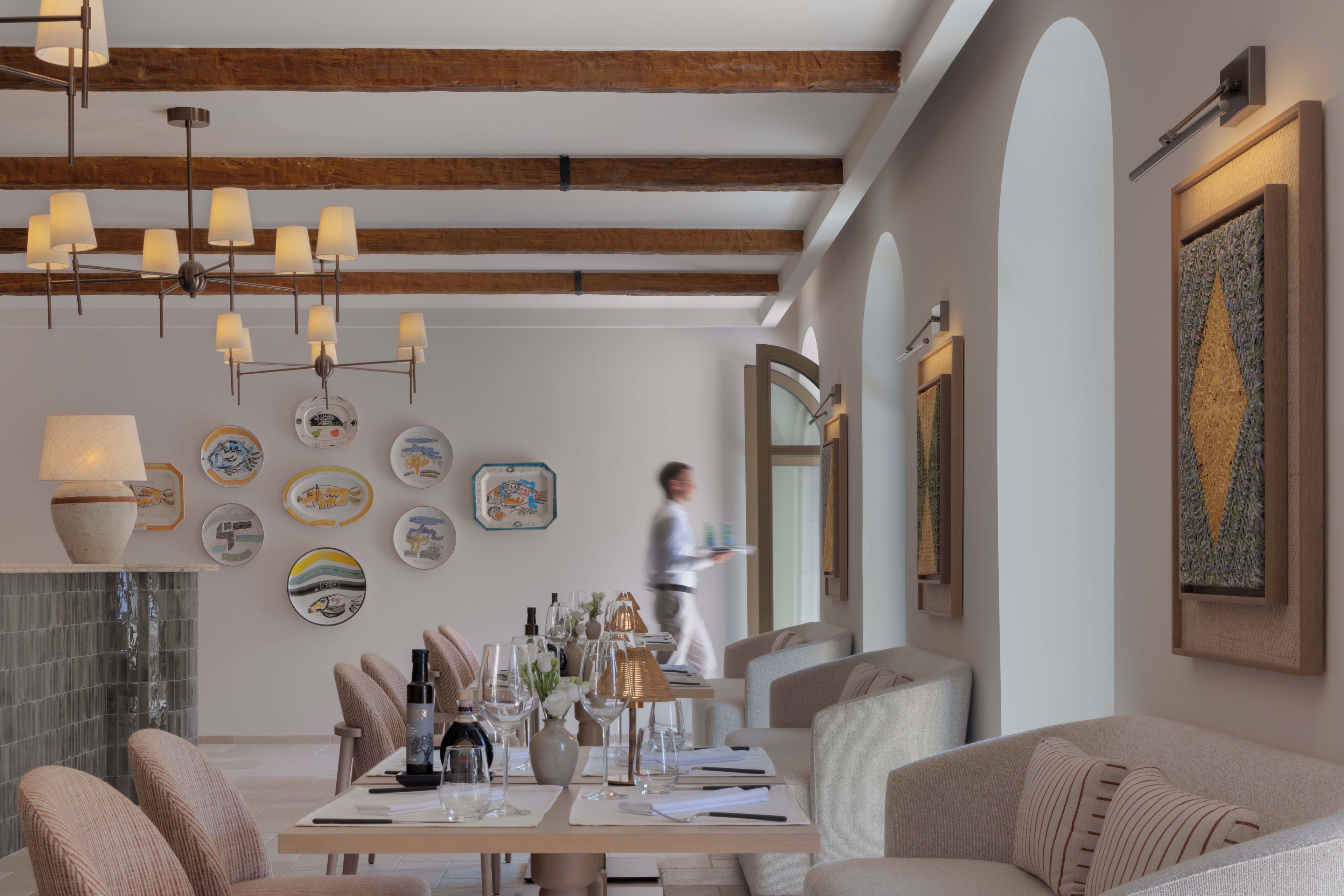 A dining area with a long table set for a meal, surrounded by cushioned seating.