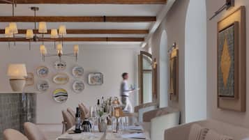 A dining area with a long table set for a meal, surrounded by cushioned seating.