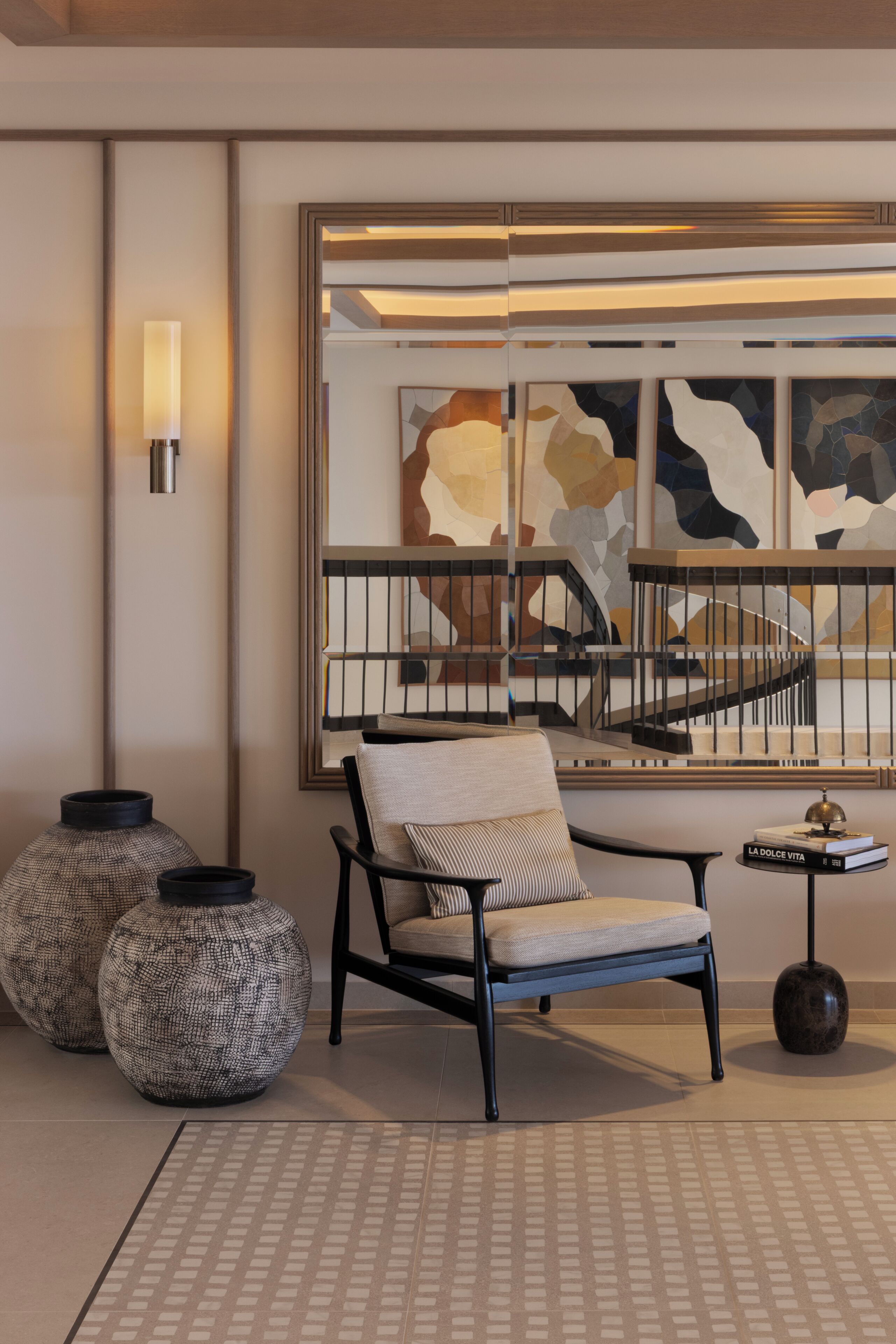 A modern living room with a large abstract painting, a sofa, two patterned vases, and a small table with a book.