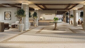 Un lobby espacioso con mostrador de recepción, amplias columnas y plantas en macetas.