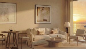 Una sala de estar moderna con un sofá, sillones, una mesa de centro y un comedor con sillas y una mesa dispuesta para dos personas.