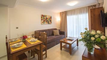 Un comedor con una mesa dispuesta para cuatro personas, un sofá y una mesita auxiliar.